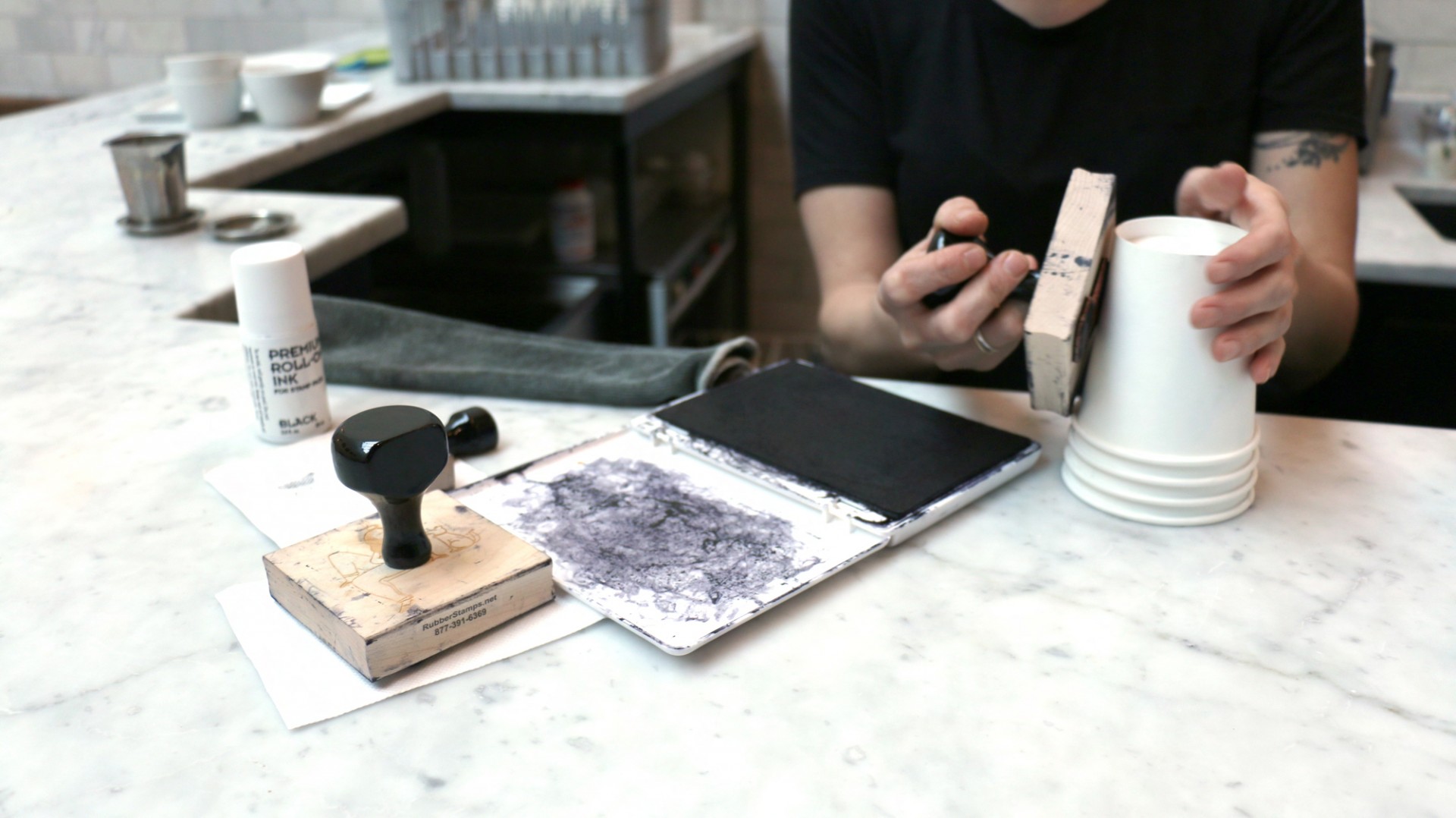 Woman stamping coffee cups with illustration