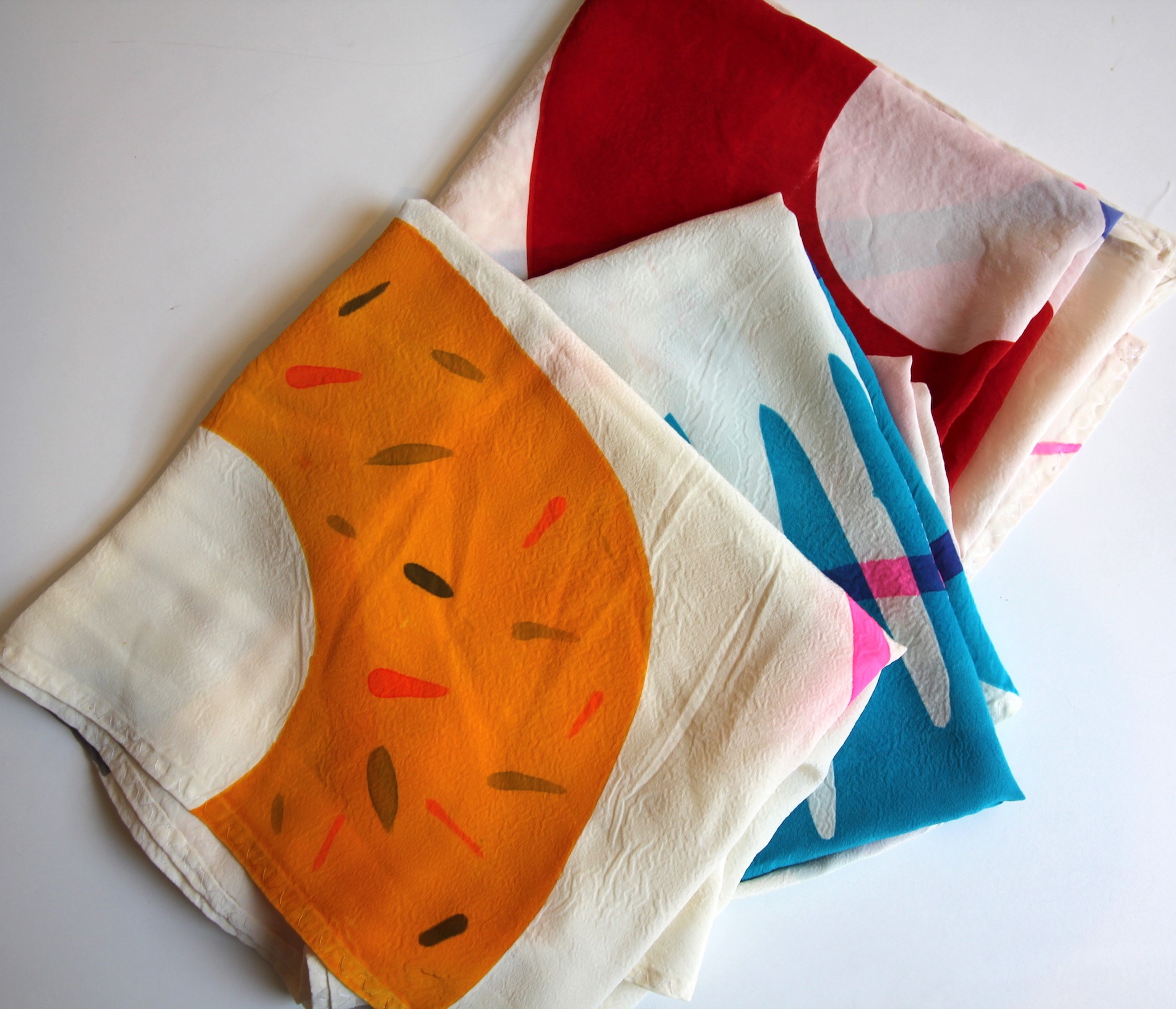 Three scarfs folded on white table. 