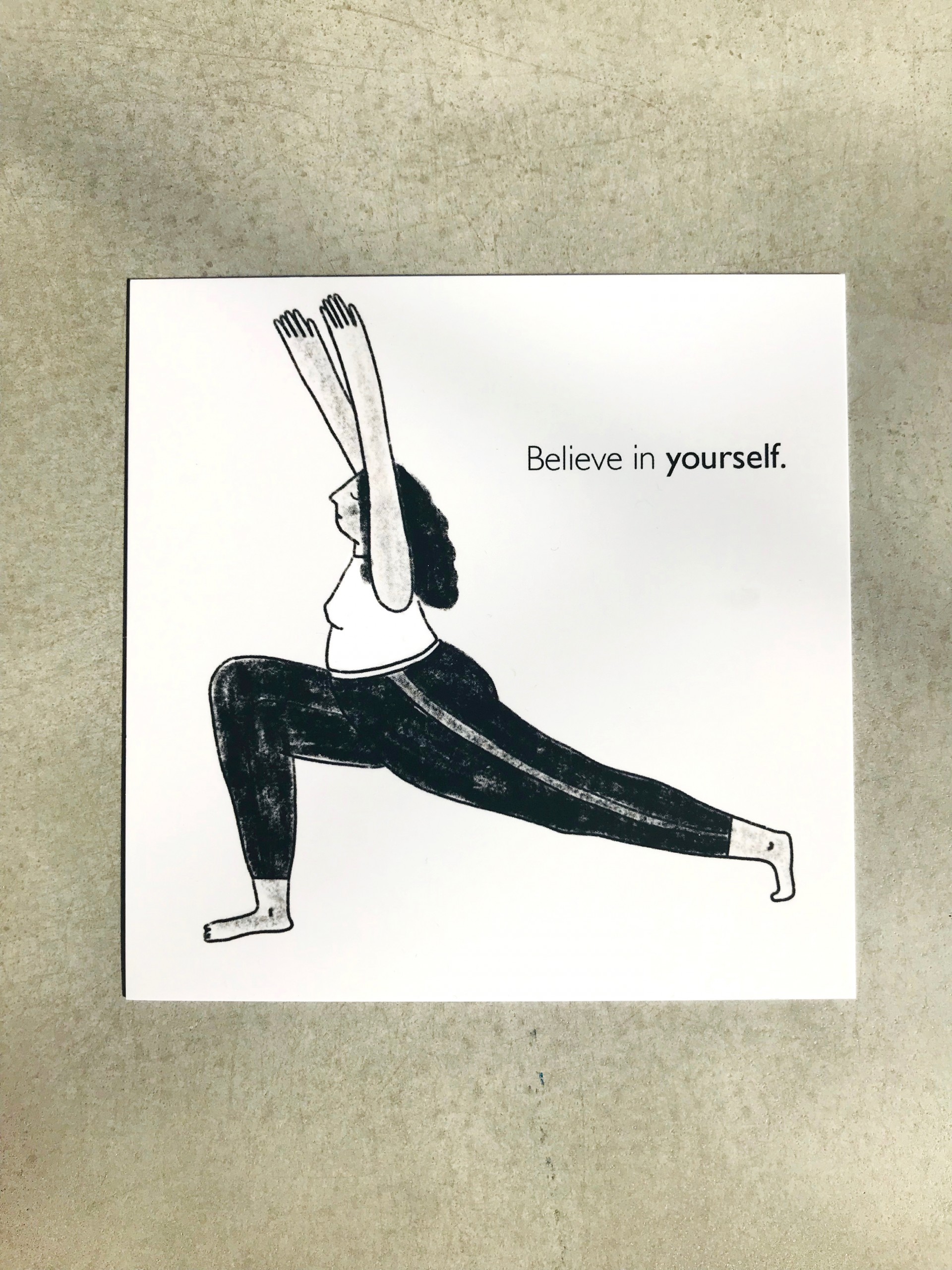 Grey square postcard with figure in yoga position. Text reads "Believe in Yourself". 