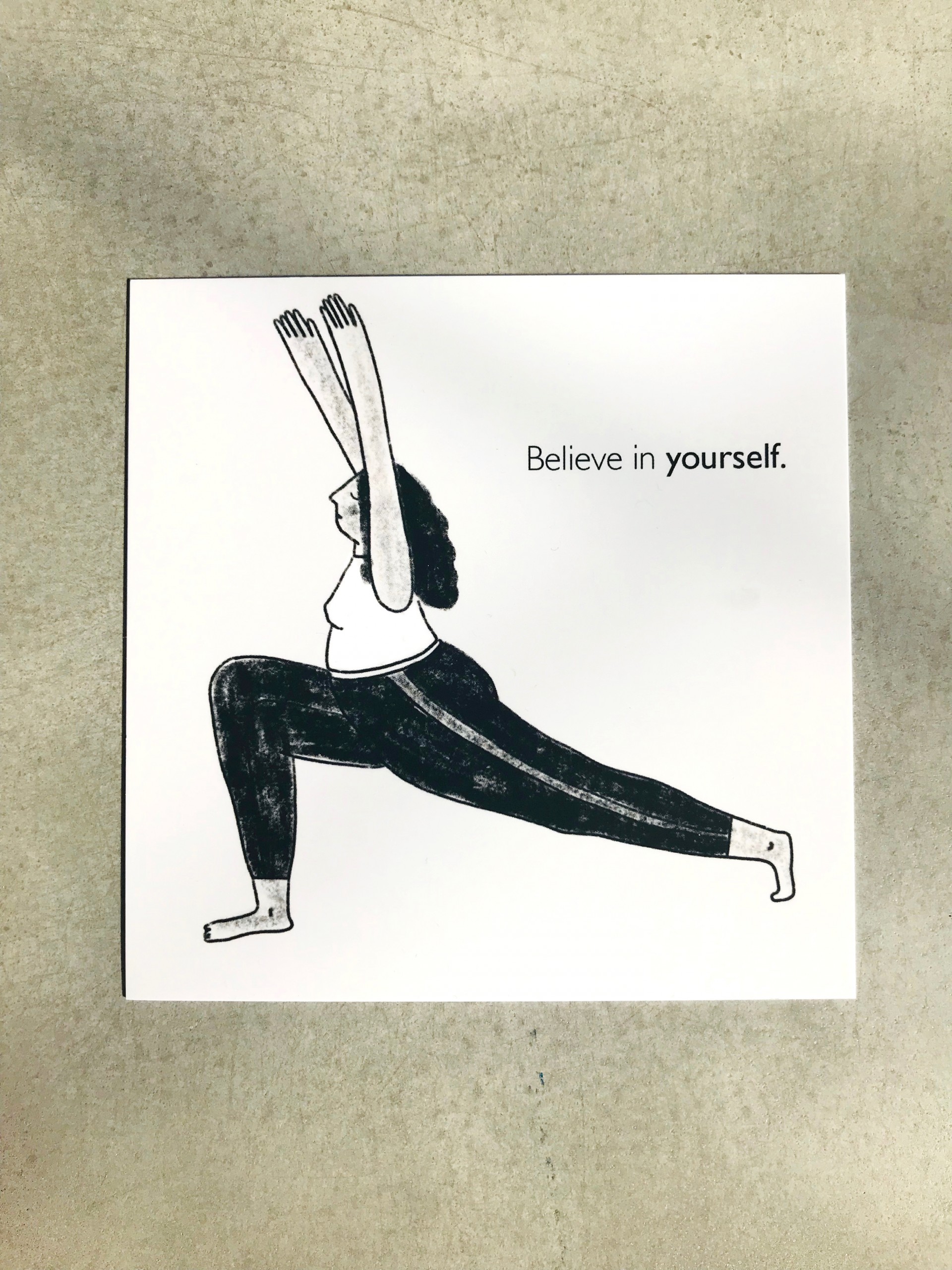 Grey square postcard with figure in yoga position. Text reads "Believe in Yourself".