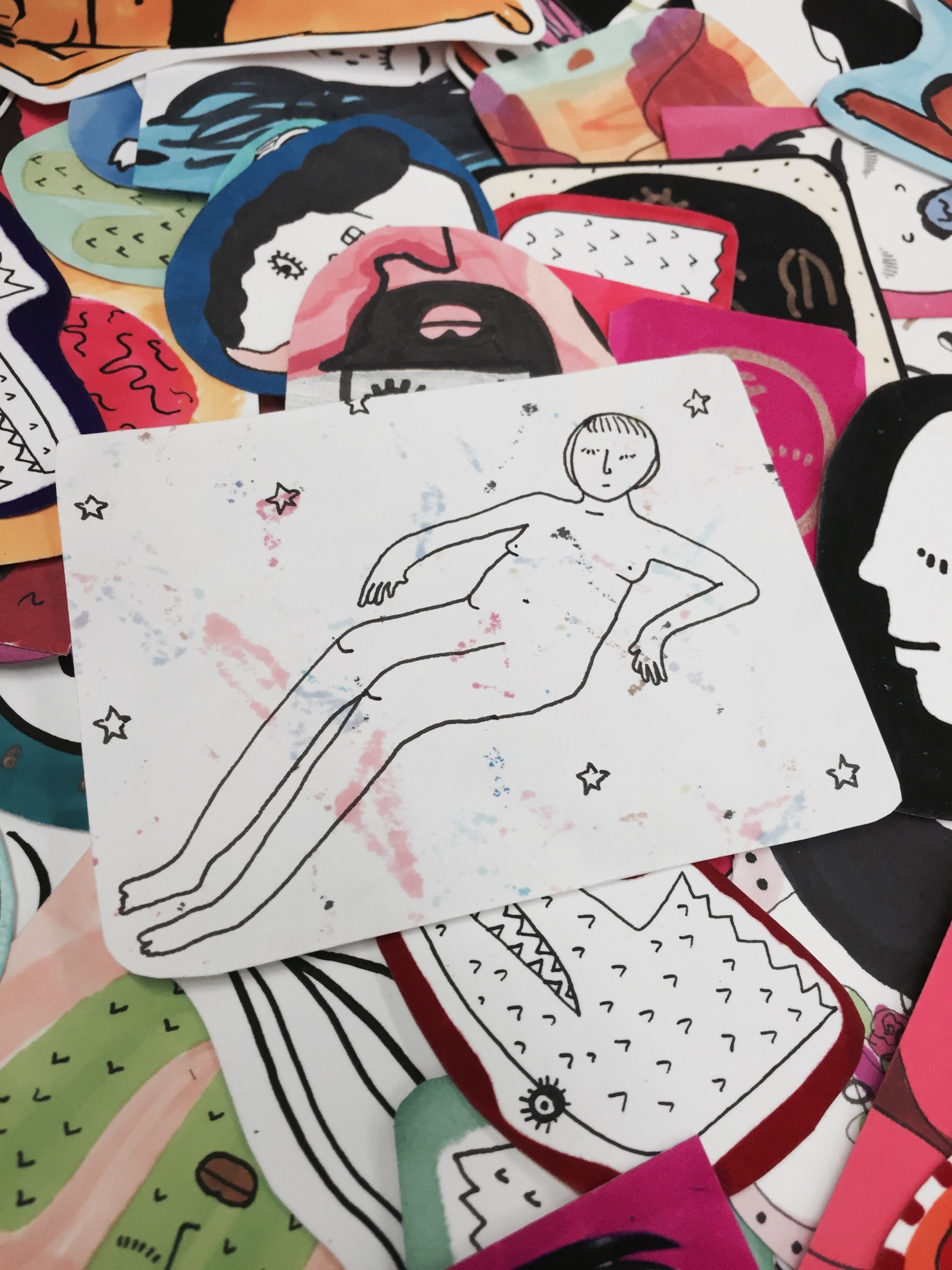 Pile of stickers. Central sticker is of naked woman in stars. 