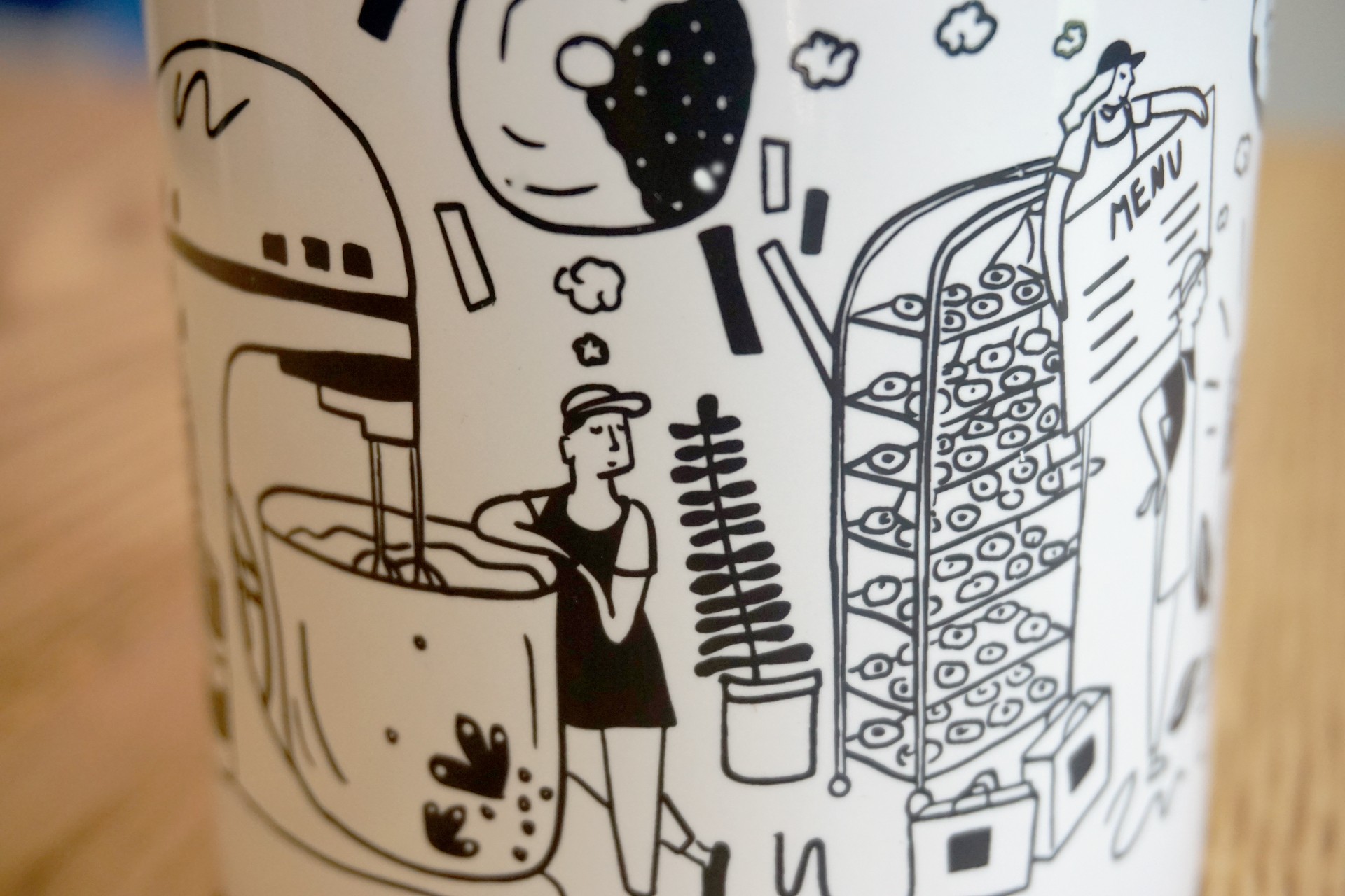 Detail of mug that shows baker leaning against oversized mixer dreaming of donuts. 