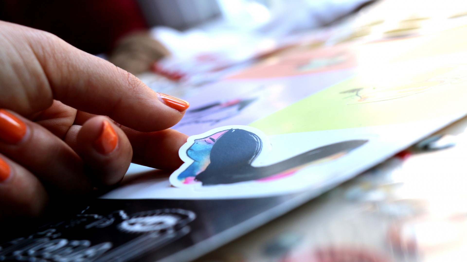 Hand peeling sticker from sticker sheet.