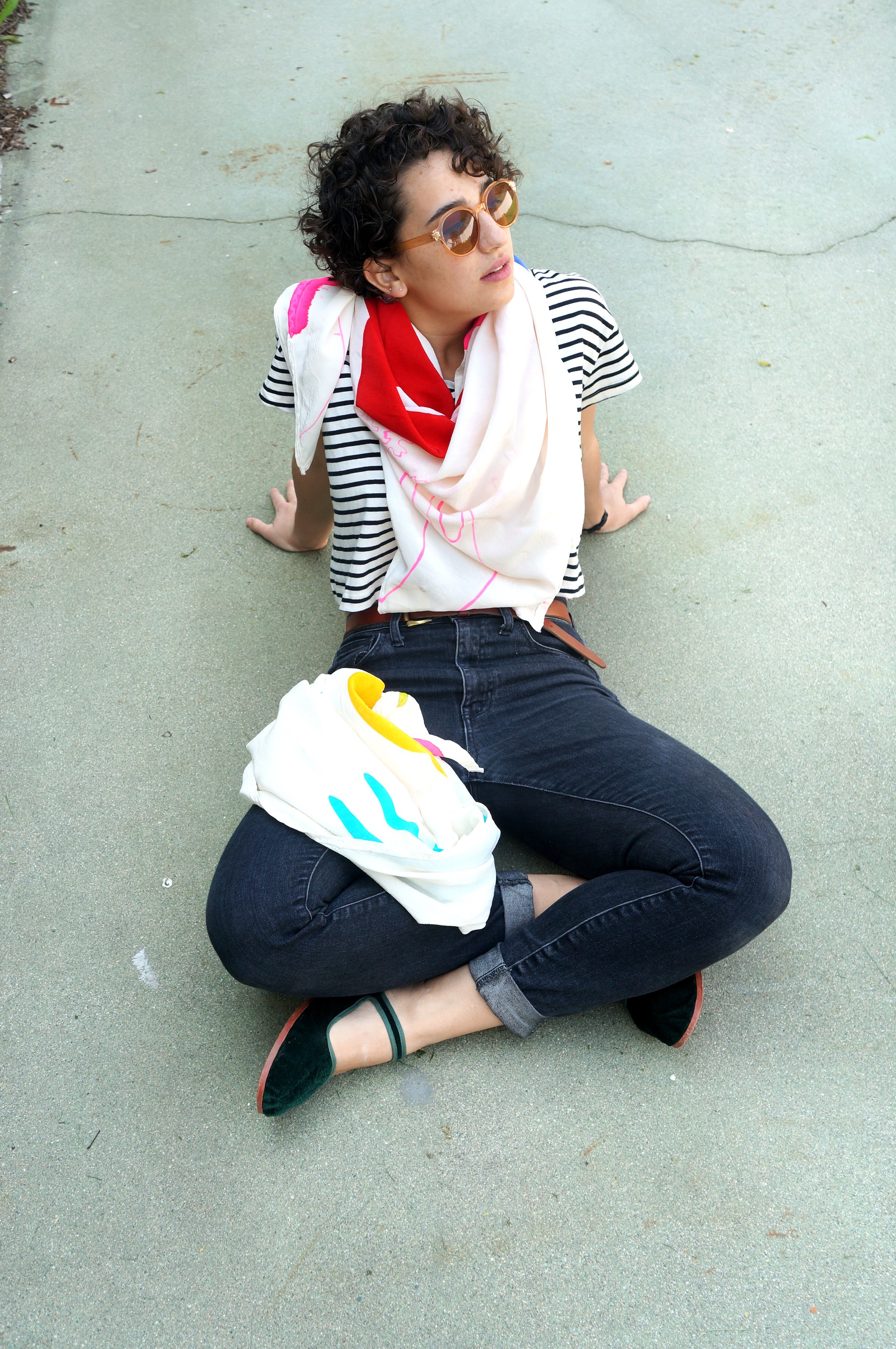 Model sitting on ground draped in scarves. 