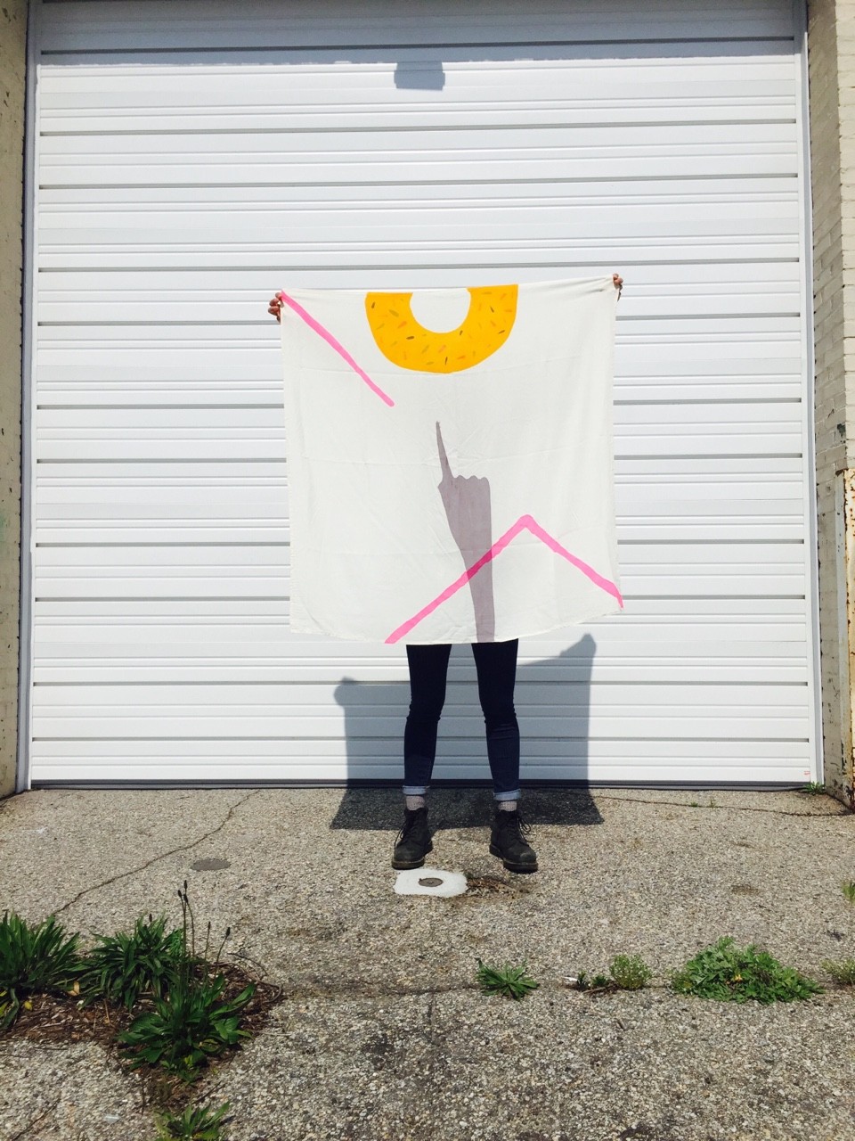 Model holding scarf against wall. Design includes a grey hand pointing to a yellow half circle.