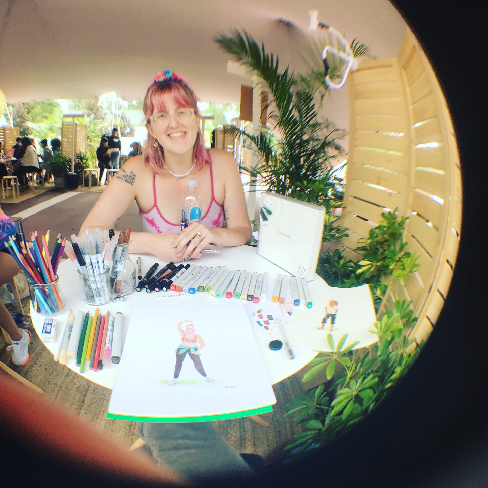 Fisheye angle photograph of portrait drawing station with markers, paper and model