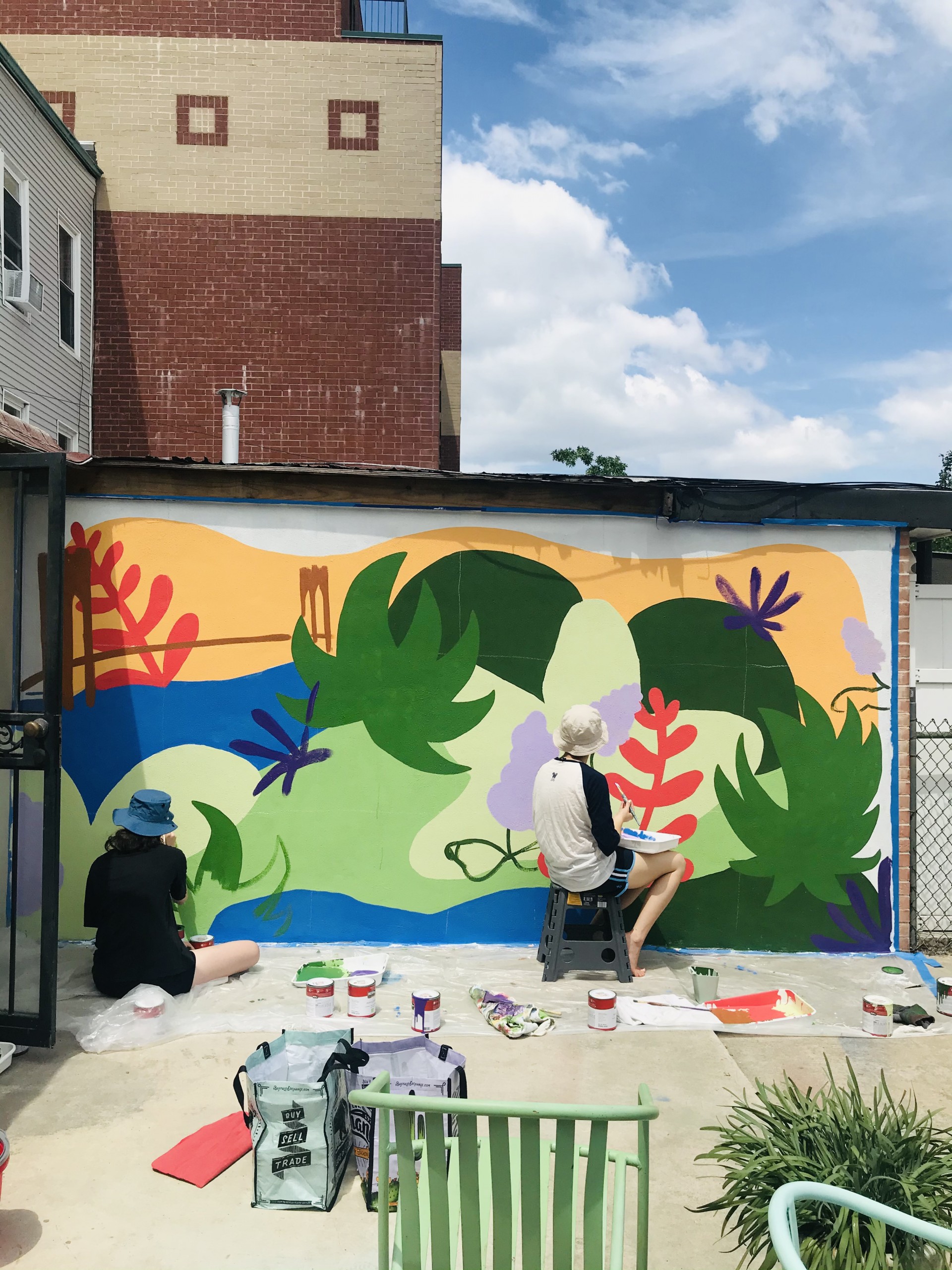 Two women painting mural.